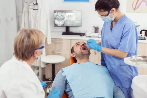 Больничная медсестра в медицинском мундире смотрит в больной рот — стоковое фото