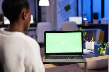 Koyu tenli serbest çalışan, yeşil ekran latop ile ofiste fazla çalışıyor.