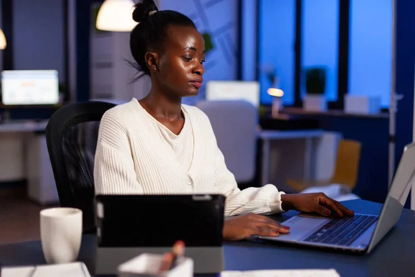 Empreendedor africano focado escrevendo no laptop tarde da noite — Fotografia de Stock