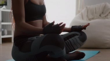 Esmer tenli sporcu kadın spor giyerek evde yoga yapıyor.