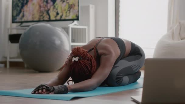 Fit atletische vrouw met zwarte huid zitten op yoga kaart tijdens aerobics ochtend workout — Stockvideo