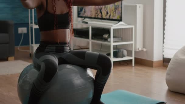 Svart passform kvinna gör yoga övningar med hjälp av yogaband på fitness boll — Stockvideo