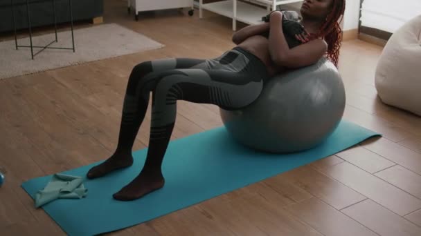 Тонка посадка чорношкіра жінка сидить на йога-свінг м'яч робить абс вправи — стокове відео