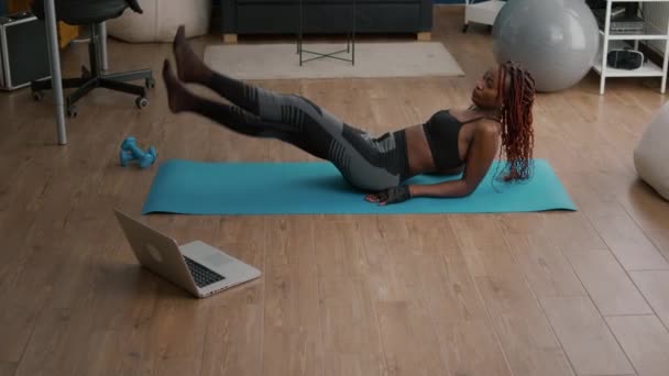 Wysportowana kobieta robi ćwiczenia nożyczek siedząc na mapie jogi — Wideo stockowe