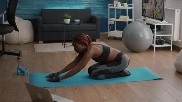 Femme mince avec peau noire assise sur une carte de yoga faisant de l'entraînement matinal de remise en forme — Video