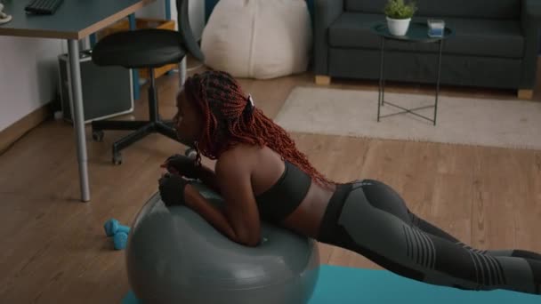 Atlético magro mulher negra alongamento muscular abdominal enquanto sentado na ioga fitness swiss ball — Vídeo de Stock