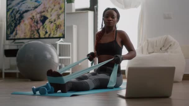 Fit μαύρη γυναίκα σε αθλητικά ρούχα κοιτάζοντας σε απευθείας σύνδεση προπόνηση στο laptop — Αρχείο Βίντεο