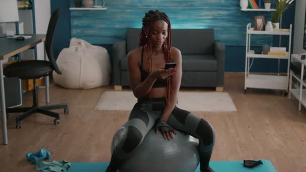 Fit atheltic femme avec peau noire portant des vêtements de sport assis sur yoga balle suisse — Video