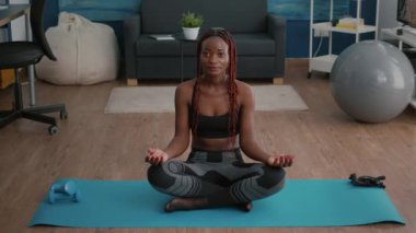 Siyahi kadın portresi lotus pozisyonu almış sabah nefes egzersizi yapıyor.