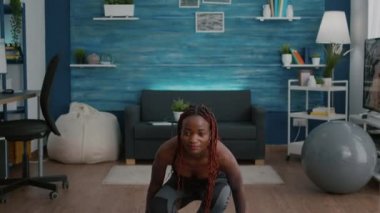 Esmer tenli zayıf atlet kadın yoga haritasına lotus pozisyonu koyuyor.