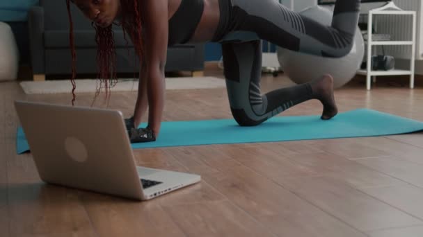 Vuxen svart kvinna som sitter på yogakartan tittar på online fitness träning — Stockvideo