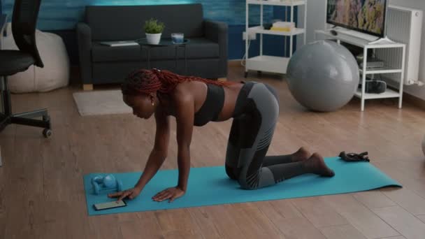 Flexibele slanke zwarte vrouw stretching body spieren zetten cronometer op de telefoon — Stockvideo