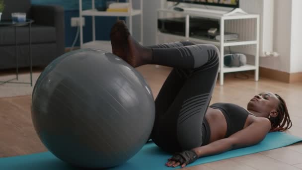 Ajuste mujer con piel negra haciendo ejercicios abdominales usando fitball flexionando los músculos abdominales — Vídeos de Stock