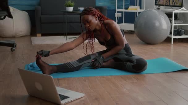 Nő sötét bőr csinál pilates edzés a nappaliban nyújtózó test izmok