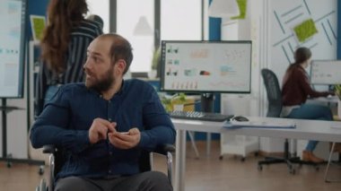 Engelli genç çalışanlar iş saatleri içinde akıllı telefonlara bakıyorlar.