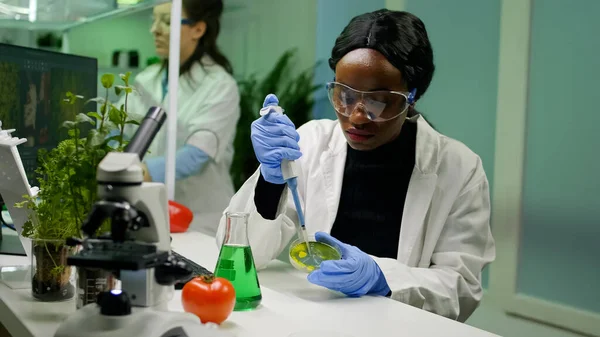 Científica química mujer africana tomando solución de ADN del tubo de ensayo —  Fotos de Stock