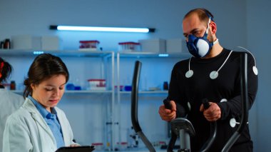 Doktor bilim sportmen dayanıklılığını ölçerken tablet üzerinde yazıyor.