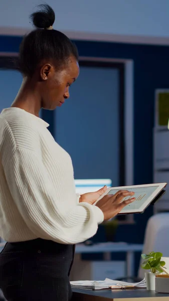Mulher negra empregada em pé no escritório e analisando gráficos — Fotografia de Stock
