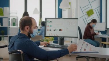 Yeni normal şirkette çalışan, yüzü maskeli, hareketsiz bir iş adamı.