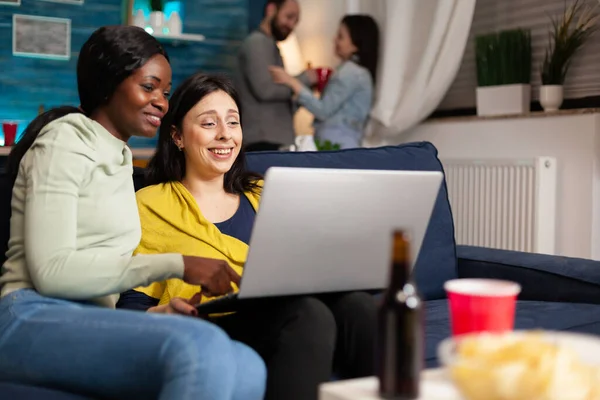 Mixed race friends talking while looking at funny video series on laptop — Stock Photo, Image