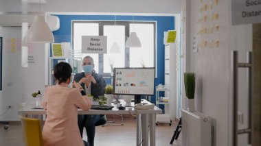 Coworkers working at business meeting wearing protective face mask