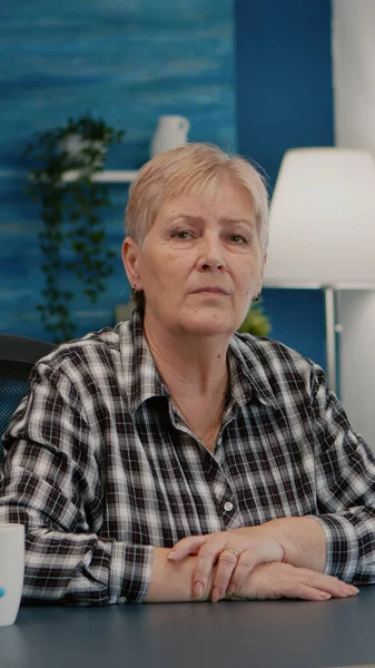 Senior woman talking and listening remote colleagues during video call — Stock Photo, Image