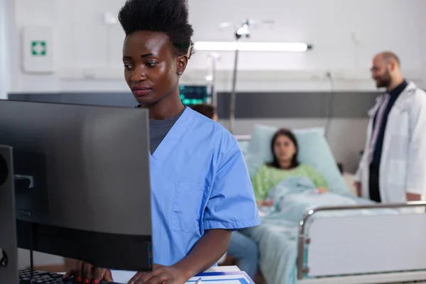 Nero medico asisstant digitando il trattamento di malattia sul computer — Foto Stock