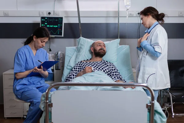 Pacient mluví s lékaři, zatímco sedí v posteli během nemoci zotavení — Stock fotografie