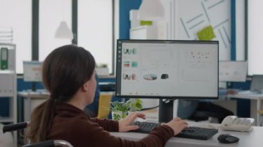 Felç olmuş finansal uzman tekerlekli sandalyede oturmuş ekonomi istatistiklerini analiz ediyor.