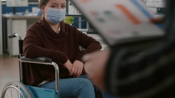 Behinderte Mitarbeiterin mit Schutzmaske blickt in Kamera — Stockvideo