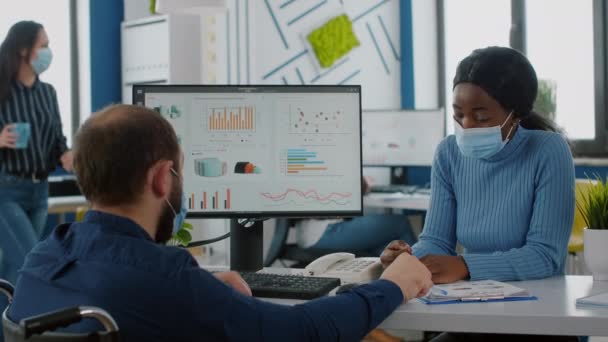 Colegas multiétnicos com máscaras trabalhando em nova empresa de inicialização normal — Vídeo de Stock