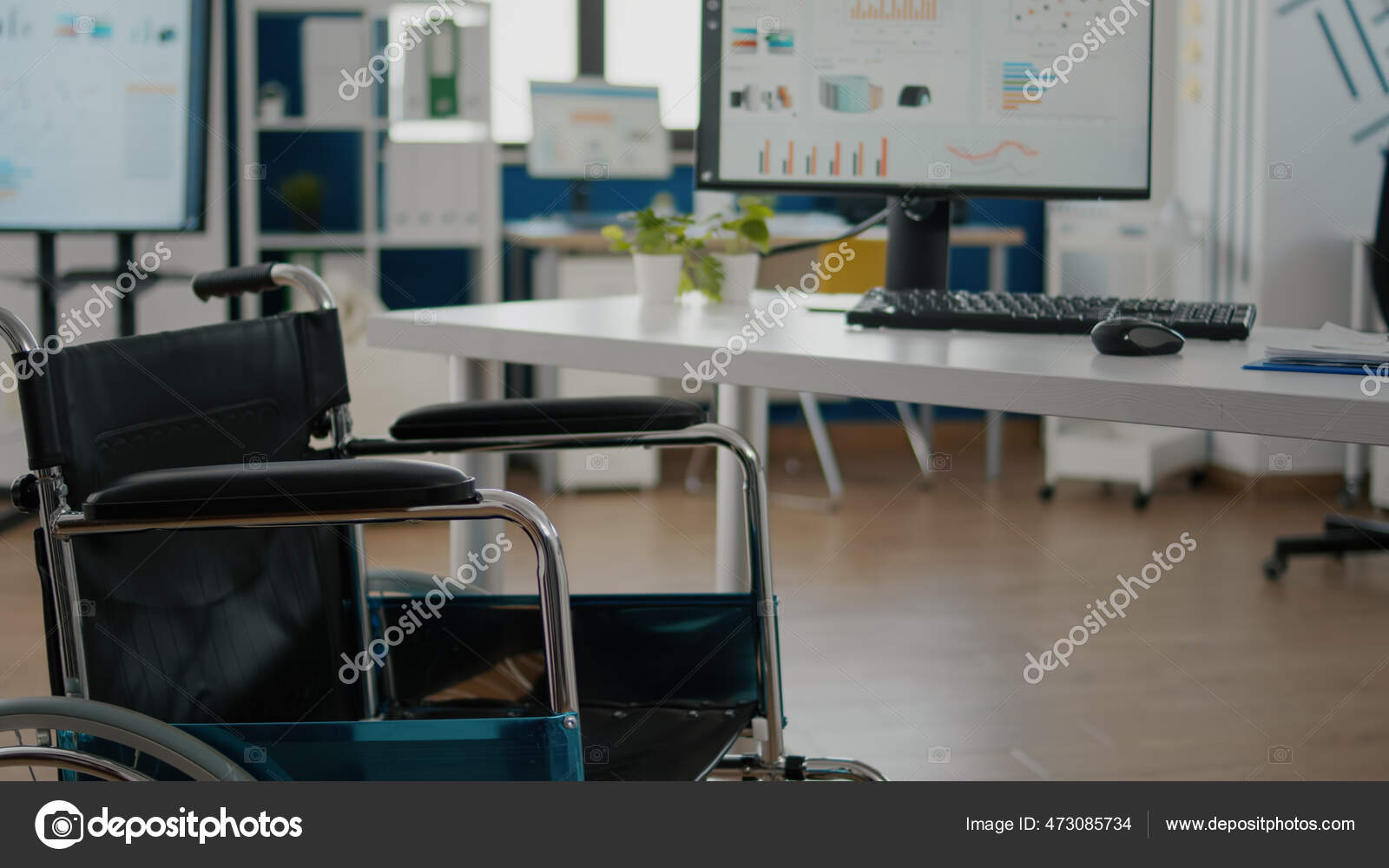 Silla de ruedas aparcada en la habitación vacía de la oficina cerca del  escritorio en la empresa de puesta en marcha — Foto de stock #473085734 ©  DragosCondreaW, image size:1600x1000