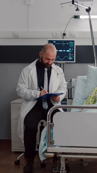 Framifrån av sjuk kvinna vilar i sängen diskuterar med onkolog man läkare — Stockfoto