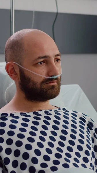 Pria sakit dengan tabung oksigen hidung beristirahat di buruk melihat ke kamera — Stok Foto