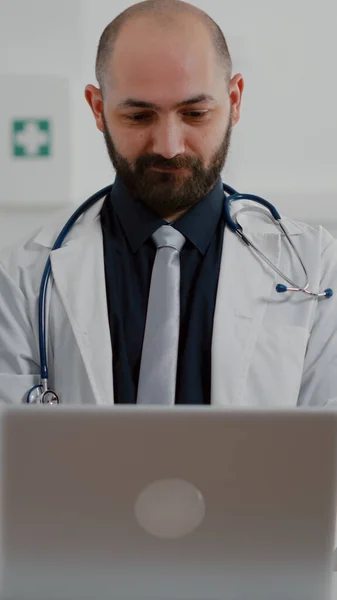 Front view of practitioner doctor typing illness expertise on computer — Stock Photo, Image