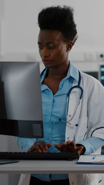 Visão frontal do médico afro-americano digitando perícia médica em informática — Fotografia de Stock