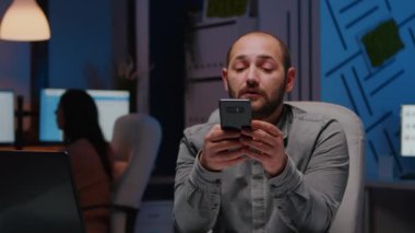 Girişimci, mali strateji planlayıcısı yazarken telefona gülümsüyor