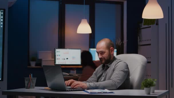 Wyczerpany biznesmen sprawdzający statystyki marketingowe na laptopie — Wideo stockowe