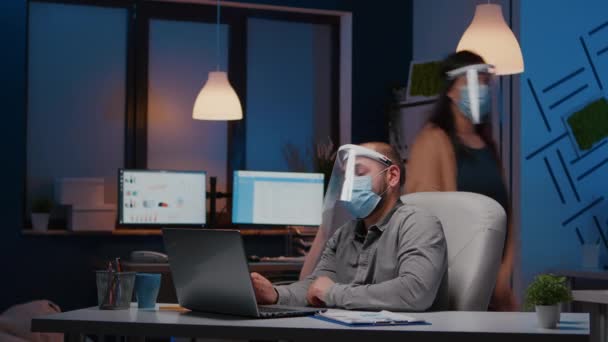 Εργασιομανής επιχειρηματίας με μάσκα προσώπου και προσωπίδα κατά του covid19 που εργάζεται στο γραφείο της εταιρείας — Αρχείο Βίντεο