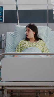 Hasta kadın hasta yetişkin yatakta dinlenirken siyahi hemşire hastalık uzmanlığını analiz ediyor.