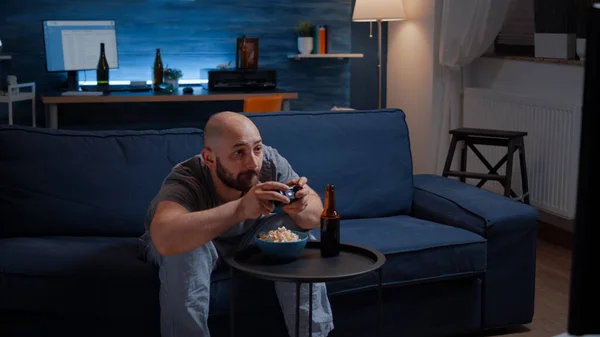 Competitivo determinado homem jogando videogame na sala de estar à noite — Fotografia de Stock