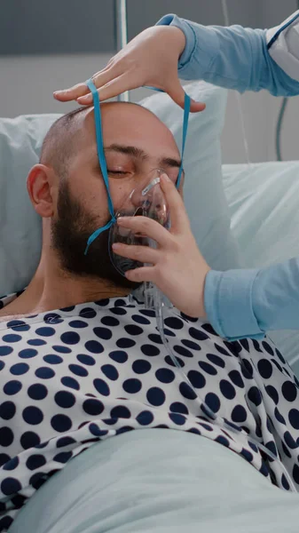 Pacient sedí v posteli, zatímco žena lékař dává kyslíkovou masku — Stock fotografie