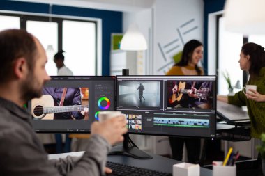 Video yönetmeni film projesini düzenliyor. Yapım sonrası yazılımı kullanarak kahve içiyor.