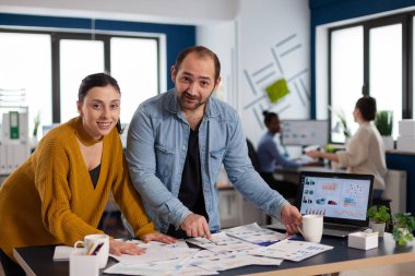 Projeyi bitirmek için çalışan kameraya gülümseyen çok ırklı yönetim