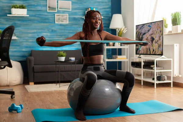 Atletica in forma gioiosa donna nera che lavora fuori muscolo posteriore con elastico — Foto Stock