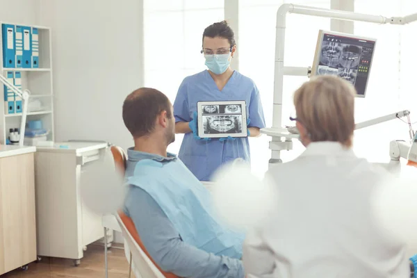 Enfermeira ortodontista segurando tablet digital com radiografia dentária na tela — Fotografia de Stock