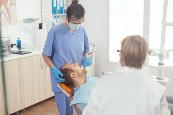 Pielęgniarka medyczna robi profesjonalne czyszczenie zębów do człowieka pacjenta — Zdjęcie stockowe
