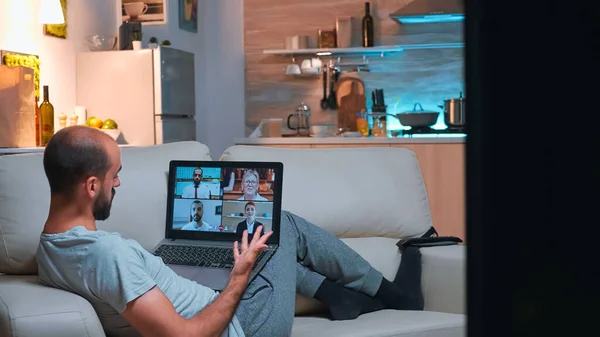 Müder Mann entspannt sich auf Sofa im Pyjama bei Online-Vidoecall-Treffen — Stockfoto