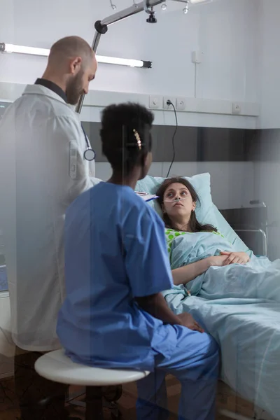 Paciente enferma descansando en la cama hablando con el médico —  Fotos de Stock