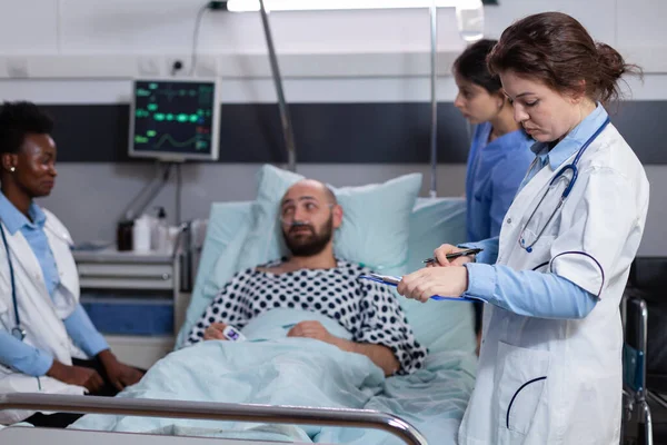 El equipo de médicos monitorea al hombre que examina los síntomas de la enfermedad monitorea la recuperación médica —  Fotos de Stock